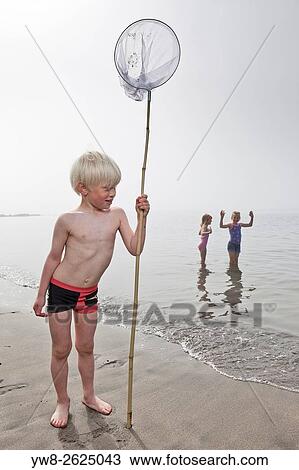 Stock Image - Boy wih net playing at the beach, Akranes, Iceland.. Fotosearch