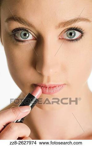 Close up of a young woman applying lipstick. View Large Photo Image Picture - Close up of a young woman applying lipstick.. Fotosearch