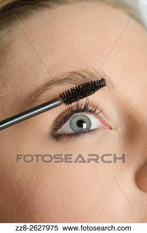 Close up of a young woman applying mascara to eyelashes. View Large Photo Image Stock Photography - Close up of a young woman applying mascara to eyelashes.. Fotosearch
