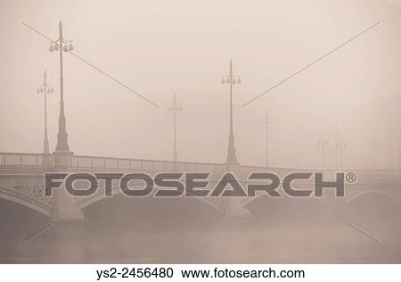 Stock Image - Empty bridge in heavy fog. Tranquil city scene with old architecture in Stockholm, Sweden.. Fotosearch