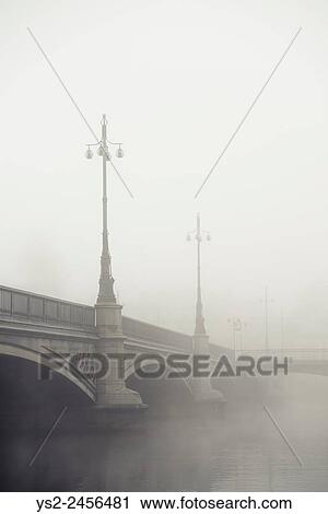 Stock Image - Empty bridge in heavy fog. Tranquil city scene with old architecture in Stockholm, Sweden.. Fotosearch