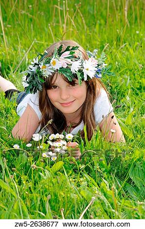 Stock Photo - Girl, ten years old and with flowers in her hair lying in a grass.. Fotosearch