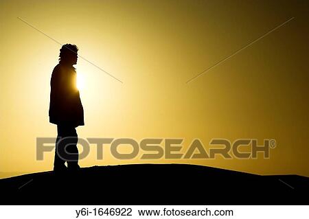 Stock Image - Guide surveys landscape from top of dune sunrise Erg Chebbi Morocco. Fotosearch