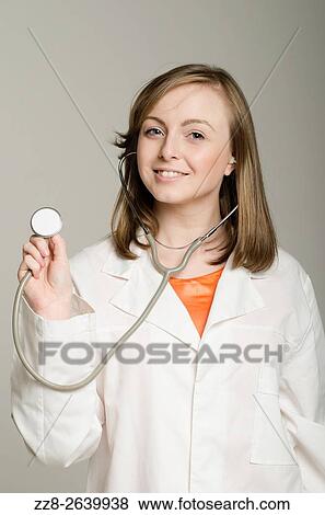 Stock Photo - Happy female doctor holding a stethoscope smiling.. Fotosearch