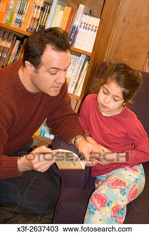 Stock Image - Hispanic father reading to daughter in bookstore age 42 and 6. Wild Rumpus Childrens Bookstore Minneapolis Minnesota USA.. Fotosearch