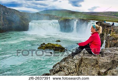 Iceland Godafoss waterfalls water falls in North Central Iceland on Ring Road with tourist sitting in red. View Large Photo Image Stock Image - Iceland Godafoss waterfalls water falls in North Central Iceland on Ring Road with tourist sitting in red.. Fotosearch