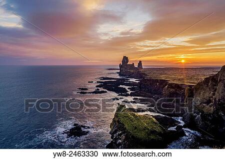 Stock Image - Londrangar sea stacks and the Thufubjarg cliffs. Londrangar-basalt volcanic dikes that formed after magma solidified, after years of erosion these sea stacks remain, Snaefellnes Peninsula, Iceland. Londrangar sea stacks and the Thufubjarg cliffs..... Fotosearch