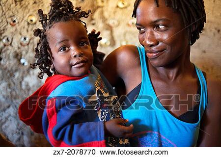 Stock Image - Portrait of a Western mother and daughter wearing her hair in braids at camp Batawana. In the vicinity of Camp Eagle Island Camp by Orient Express, outside the Moremi Game Reserve in Botswana there is a camp where hundreds of Indians from the tribe.... Fotosearch