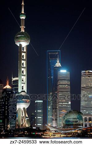 Stock Image - Pudong Skyline, by night, Shanghai, China. Skyline of Pudong as seen from the Bund, with landmark Oriental Pearl tower and Jin Mao tower, Shanghai, China. The word bund means an embankment or an embanked quay. The word comes from the Persian word.... Fotosearch