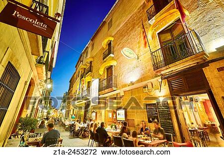 Stock Image - Restaurant terraces at Loreto street by night. Denia. Alicante. Valencia Community. Spain.. Fotosearch