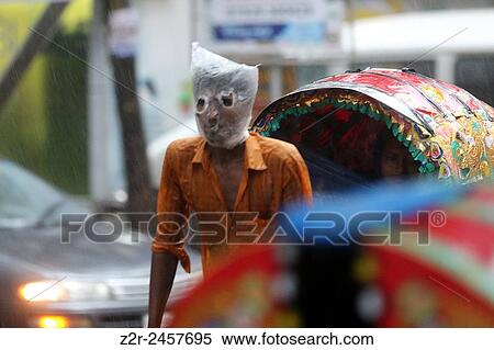 Rickshaw puller wears a plastic bag on his head and face as he carries passengers in a rain-soaked street of Dhaka, Bangladesh, 13 June 2015. City dwellers got relieve in the form of rain after suffering during hot weather over the past few days.... View Large Photo Image Stock Photography - Rickshaw puller wears a plastic bag on his head and face as he carries passengers in a rain-soaked street of Dhaka, Bangladesh, 13 June 2015. City dwellers got relieve in the form of rain after suffering during hot weather over the past few days..... Fotosearch