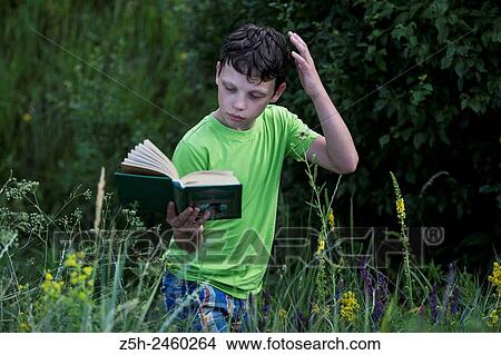 Picture - Russia. Belgorod region. Solomino village. The boy in the meadow with a book.. Fotosearch