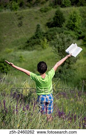 Stock Image - Russia. Belgorod region. Solomino village. The boy in the meadow with a book.. Fotosearch