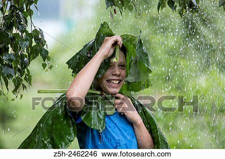 Stock Photograph - Russian Federation. Belgorod region. The boy in the rain uryvshiysya leaves of the plant.. Fotosearch