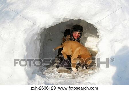 Stock Photo - Siberia. Snowy winter. A child with a puppy playing in the snow drifts.. Fotosearch