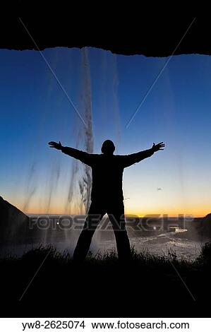 Picture - Silhouette of man behind Seljalandsfoss Waterfall, Iceland.. Fotosearch