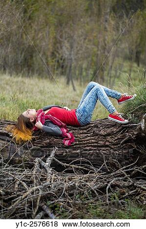 Teen girl in denim pants and sneakers in nature across fallen tree View Large Photo Image Stock Photo - Teen girl in denim pants and sneakers in nature across fallen tree. Fotosearch
