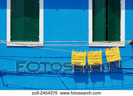 Stock Photography - Three yellow cushions hanging on line outside blue painted house, Burano, Venetian Lagoon, Veneto, Italy, Europe.. Fotosearch
