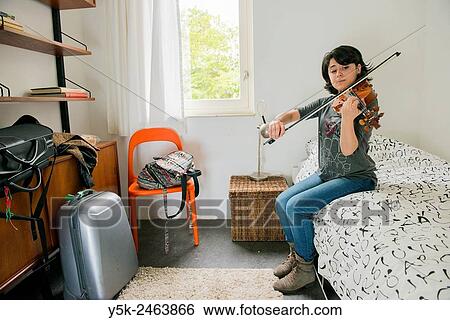 Tilburg, Netherlands. Female Italian violinist sitting on the bed of her Airbnb guest room, while practising with her violin. View Large Photo Image Stock Photograph - Tilburg, Netherlands. Female Italian violinist sitting on the bed of her Airbnb guest room, while practising with her violin.. Fotosearch