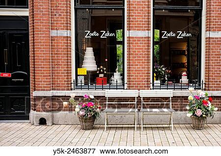 Tilburg, Netherlands. Terrace chairs and pots with flowers in front of the shop windows of Zoete Zaken, a pie store in down town Tuinstraat View Large Photo Image Stock Photo - Tilburg, Netherlands. Terrace chairs and pots with flowers in front of the shop windows of Zoete Zaken, a pie store in down town Tuinstraat. Fotosearch