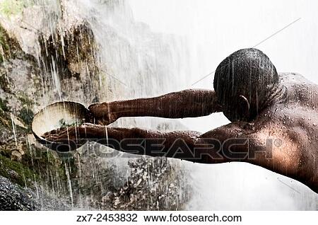 Voodoo Festival in Saut dEau, Haiti. A man collects the water falling from the waterfall to purify her. On this feast of voodoo tradition to the Iwa goddesses are honored with Christian ceremonies such as the veneration of the Virgin of Miracles... View Large Photo Image Stock Image - Voodoo Festival in Saut dEau, Haiti. A man collects the water falling from the waterfall to purify her. On this feast of voodoo tradition to the Iwa goddesses are honored with Christian ceremonies such as the veneration of the Virgin of Miracles.... Fotosearch