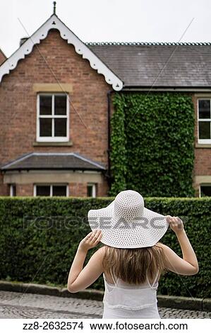 Picture - Woman in hat outside the house.. Fotosearch