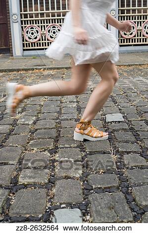 Woman running on a cobbled street. View Large Photo Image Picture - Woman running on a cobbled street.. Fotosearch