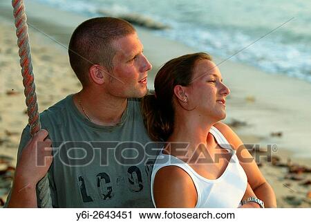 Stock Image - Young couple embrace on swing Teluk Nipah beach Pulau Pangkor island Malaysia.. Fotosearch