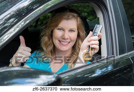 Stock Image - Young teenage girl age 16 with first driving of a car showing off her keys MR model released.. Fotosearch