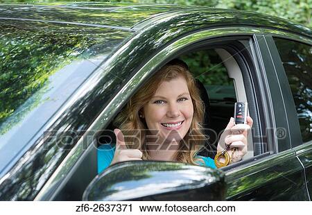 Stock Image - Young teenage girl age 16 with first driving of a car showing off her keys MR model released.. Fotosearch