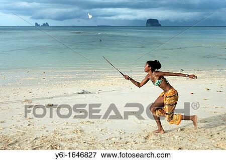 Stock Photo - Young woman in bikini sarong plays badminton on beach Ko Bulon Leh island Thailand. Fotosearch