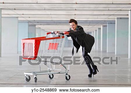 Stock Photo - Young woman pushing empty shopping cart. Fotosearch