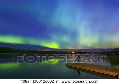 Woman Sitting On Dock In Chair On 6 Mile Lake With Northern Lights Overhead Anchorage Alaska Picture