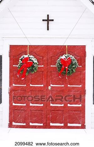 Christmas Wreaths Hang On Bright Red Double Doors At An