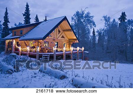 Log Cabin In The Woods Decorated With Christmas Lights At Twilight