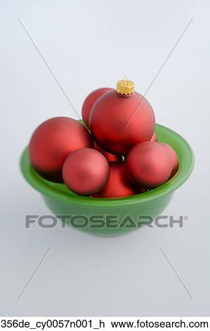 Red Christmas Balls Piled Up In Green Glass Bowl With White