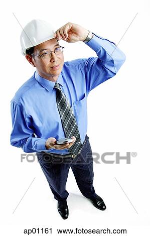 Stock Photography - Man wearing hardhat standing, holding PDA, looking away. Fotosearch - Search Stock Photos, Pictures, Prints, Images, and Photo Clip Art