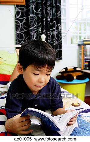 Boy in bedroom, lying on bed, reading a book View Large Photo Image Stock Photography - Boy in bedroom, lying on bed, reading a book. Fotosearch