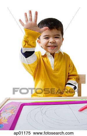 Boy sitting, smiling at camera, raising hand View Large Photo Image Stock Photography - Boy sitting, smiling at camera, raising hand. Fotosearch