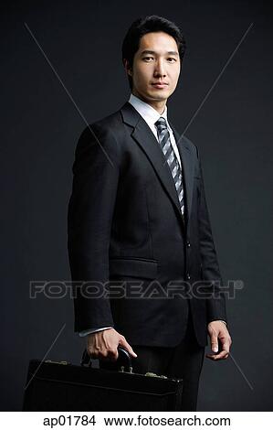 Businessman carrying briefcase, looking at camera View Large Photo Image Picture - Businessman carrying briefcase, looking at camera. Fotosearch