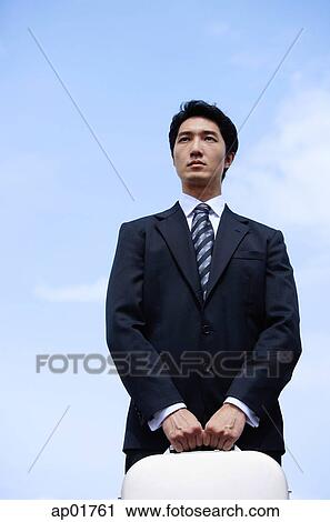 Stock Image - Businessman carrying briefcase, looking away. Fotosearch