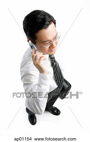 Picture - Businessman carrying briefcase, using mobile phone. Fotosearch
