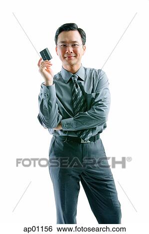 Businessman holding credit card, arms crossed, looking at camera View Large Photo Image Stock Photograph - Businessman holding credit card, arms crossed, looking at camera. Fotosearch