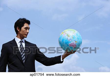 Picture - Businessman holding globe, arms outstretched. Fotosearch