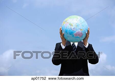 Businessman holding globe, covering his face View Large Photo Image Stock Image - Businessman holding globe, covering his face. Fotosearch