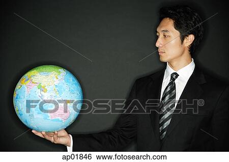 Stock Photograph - Businessman holding globe in one hand. Fotosearch