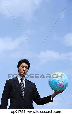 Businessman holding globe, looking at camera View Large Photo Image Stock Photography - Businessman holding globe, looking at camera. Fotosearch