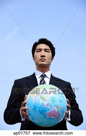 Businessman holding globe with both hands, looking away View Large Photo Image Stock Photo - Businessman holding globe with both hands, looking away. Fotosearch