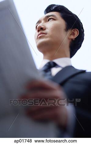 Businessman holding newspaper, looking away View Large Photo Image Stock Photo - Businessman holding newspaper, looking away. Fotosearch