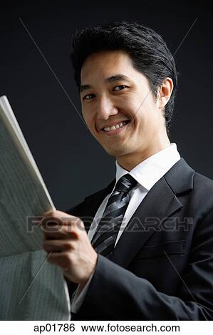 Businessman holding newspaper, smiling View Large Photo Image Stock Photograph - Businessman holding newspaper, smiling. Fotosearch